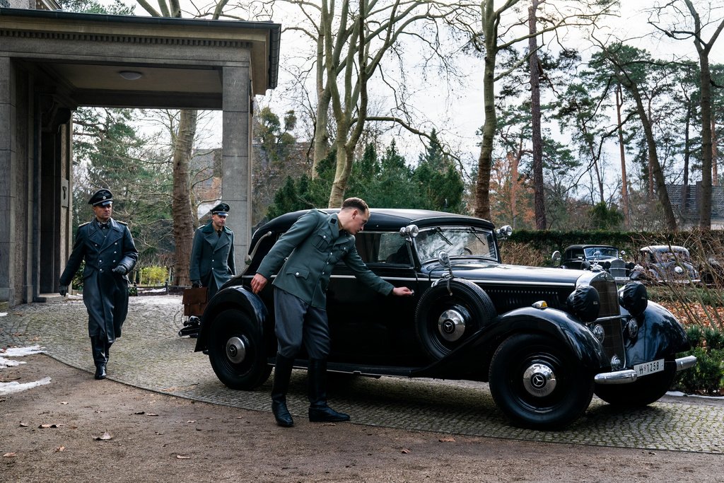 Reinhard Heydrich (Philipp Hochmair, l.), Chef des Reichssicherheitshauptamts, Chef der Sicherheitspolizei und des SD, verlässt nach der Besprechung die Villa und eilt zu seiner Limousine.