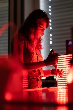 Die Doktorandin Saskia Frank arbeitet im abgedunkelten Labor und unter Nutzung von rotem Licht mit einem Hydrogel aus fluoreszierenden Proteinen / © WWU - Peter Leßmann